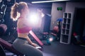 Girl posing in the gym with a bottle in her hands, sitting on a bench. Horizontal photo Royalty Free Stock Photo