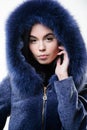 Girl posing hooded fur coat. Female with makeup wear dark blue soft fur coat. Woman wear hood with fur. Fashion concept