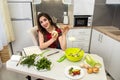 Girl posing at a kitchen table while prepares a salad of different vegetables and greens for a healthy lifestyle