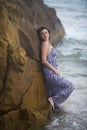 Girl posing leaning on rock on ocean background