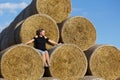 Girl posing near a stack of straw. Straw rolls, stacked in a pyramid Royalty Free Stock Photo