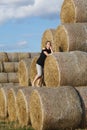 Girl posing near a stack of straw. Straw rolls, stacked in a pyramid Royalty Free Stock Photo