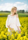 Girl posing in rape seed flowers field posing in white dress at sunny day Royalty Free Stock Photo