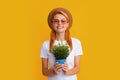 Girl potted plants on yellow studio. Woman planting flowers in pot.