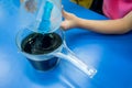 A girl pouring blue chemical solution into acid solution until t