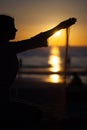 Girl pouring sand at sunset