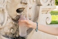A girl pouring water in a bottle from a drinking fountain in the form of a human face in Austria. Royalty Free Stock Photo