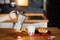 The girl pours hot coffee in a mug with the words I LOVE YOU from red paper on the table with the cake, against the background of Royalty Free Stock Photo