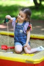 Girl pours out sand in the sandbox on the Royalty Free Stock Photo