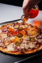 The girl pours a pizza with Bavarian sausages and jalapeno with hot pepper oil Royalty Free Stock Photo