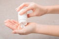 The girl pours a white tablet or vitamins or food Supplement into her hand from a white bottle. Concept of treatment, prevention