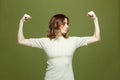 Girl power. Confident proud strong independent young woman showing arms muscles, demonstrate biceps on green background