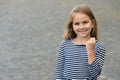 Girl power. Happy girl show fist outdoors. Beauty look of child girl. Little kid smile in stripy top. Casual style