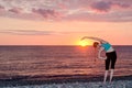 Girl practicing yoga on the beach. View from the back, sunset Royalty Free Stock Photo