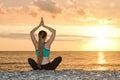 Girl is practicing yoga on the beach. View from the back, sunset Royalty Free Stock Photo