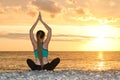 Girl is practicing yoga on the beach. View from the back, sunset Royalty Free Stock Photo