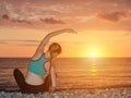 Girl practicing yoga on the beach. View from the back, sunset Royalty Free Stock Photo