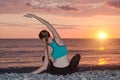 Girl practicing yoga on the beach. View from the back, sunset Royalty Free Stock Photo