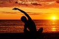 Girl practicing yoga on the beach. View from the back, sunset, silhouettes Royalty Free Stock Photo