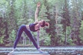 Girl practicing yoga, doing Utthita Trikonasana exercise, extended triangle pose on the lake. The concept of appeasement,