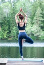 Girl  practicing yoga Tree pose, Vrikshasana   on the lake.  The concept of appeasement,  healthy lifestyle Royalty Free Stock Photo