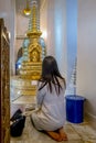 A girl prays on her knees inside the famous Wat Saket temple in Bangkok, Thailand, known as Golden Mountain