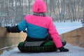 The girl prepared to roll down the ice slide in the winter on an inflatable sled