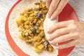 Girl prepares food from pita bread and vegetable puree with chopped eggplant and zucchini on a red plate on a black-white wooden Royalty Free Stock Photo