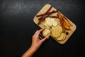 Girl prepares snacks top view. female hand takes bread with cheese from a common plate of snacks. sausage, camembert, suluguni on Royalty Free Stock Photo