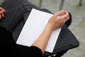 A girl is preparing to fill out a blank form, write an essay or dictation, sitting on a school chair with a writing stand. View