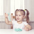 Girl preschooler sits at a table and sculpts from turquoise dough for modeling