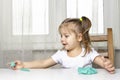 girl preschooler sits at a table and sculpts from turquoise dough for modeling. activities with children at home on self-isolation