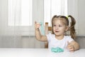 Girl preschooler sits at a table and sculpts from turquoise dough for modeling. activities with children at home on self-isolation