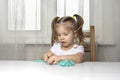 Girl preschooler sits at a table and sculpts from turquoise dough for modeling