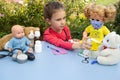 A girl preschooler sprinkles with medicine a teddy bear. A child plays doctor on the street Royalty Free Stock Photo