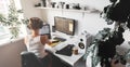 Girl programmer in the modern developer workplace for writing code with white computer desktop and comfy armchair.