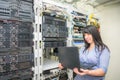 The girl programmer stands near the racks with computer equipment. System administrator to configure network protocols. A woman Royalty Free Stock Photo