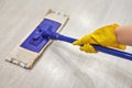 Girl in protective gloves cleaning floor using flat wet mop Royalty Free Stock Photo