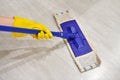 Girl in protective gloves cleaning floor using flat wet mop Royalty Free Stock Photo