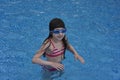 Girl with protective goggles and red swimsuit splashing in swimming pool. Adorable little girl in outdoor swimming pool Royalty Free Stock Photo