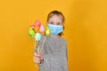 A girl in a protective mask from a coronavirus holds Easter eggs in her hand on a holiday Royalty Free Stock Photo