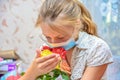 A girl in a protective mask holds a bouquet of flowers and sniffs roses, quarantined for the duration of the covid-19 virus