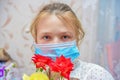 A girl in a protective mask holds a bouquet of flowers and sniffs roses, quarantined for the duration of the covid-19 virus