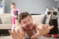 Girl pulling fathers foot and want to play, man scream on floor carpet at home Royalty Free Stock Photo