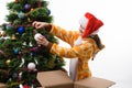 Girl pulls out of the box Christmas tree ball and hangs on the Christmas tree Royalty Free Stock Photo