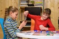 A girl pulls out a card from another girl`s hand while playing a board game