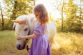 Girl in purple dress hugging white unicorn horse. Dreams come true. Fairy tale Royalty Free Stock Photo