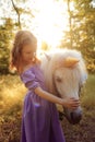 Girl in purple dress hugging white unicorn horse. Dreams come tr Royalty Free Stock Photo