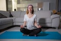 A girl in a purple scarf and in sportswear sits in a lotus pose on a yoga mat Royalty Free Stock Photo