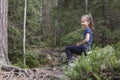 The girl in the woods with a sprig of blueberries sat on a stone